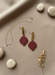Burgundy earrings flatlay with gold accents
